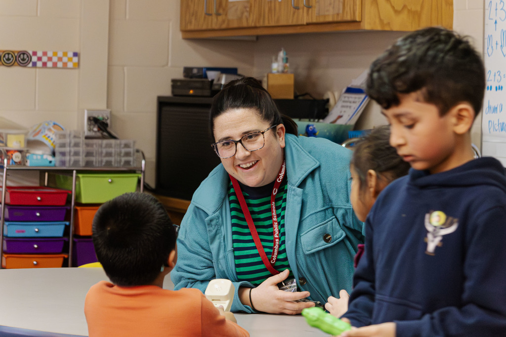 Staff member working with students on how to dial their phone number on a phone