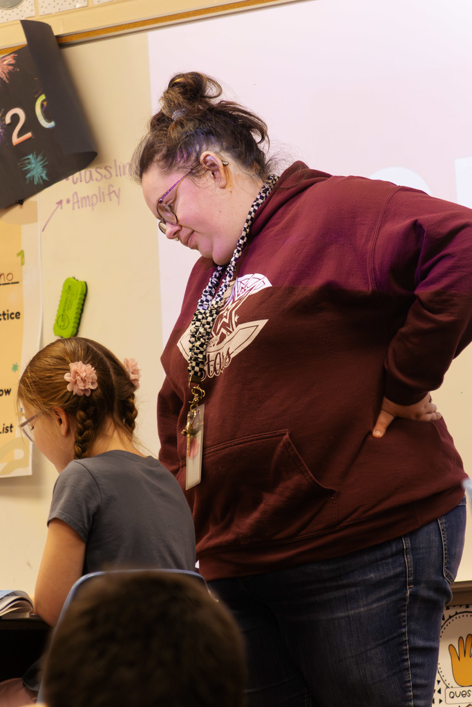 A staff member supporting a student as they work on their assignment in class