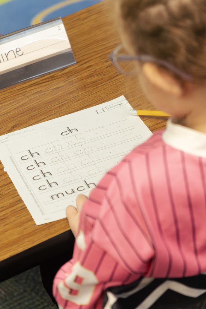 Female student wearing pink is working on writing "ch"