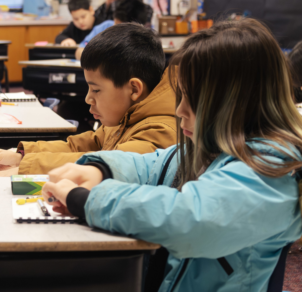 a male and female student completing workbook assignments