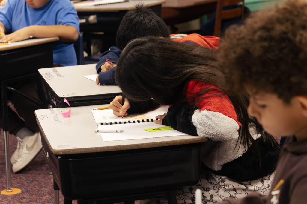 3 students completing work book assignments in class
