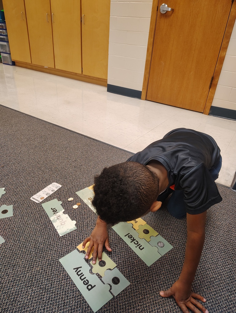 Male student working on identifying coins through a puzzle activity.