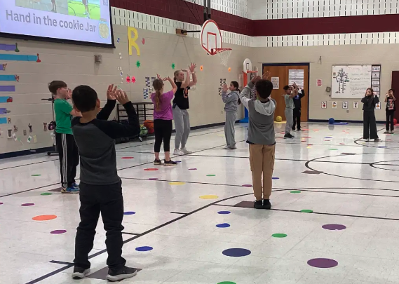 Coach showing students how to shoot a basketball