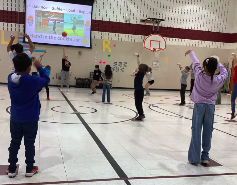 Coach showing students how to shoot a basketball