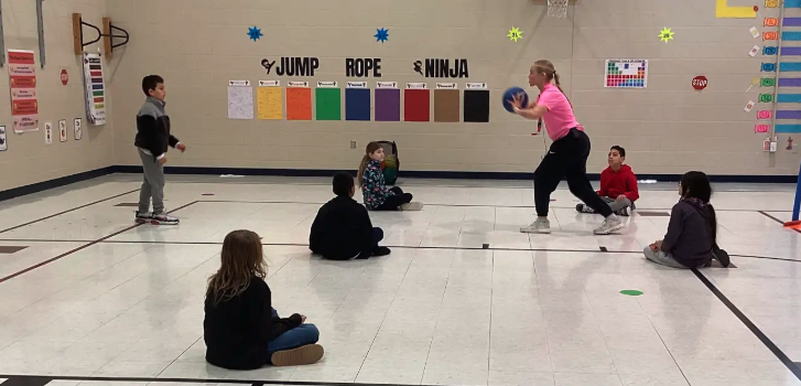 Coach Harrison passing a basketball to a student