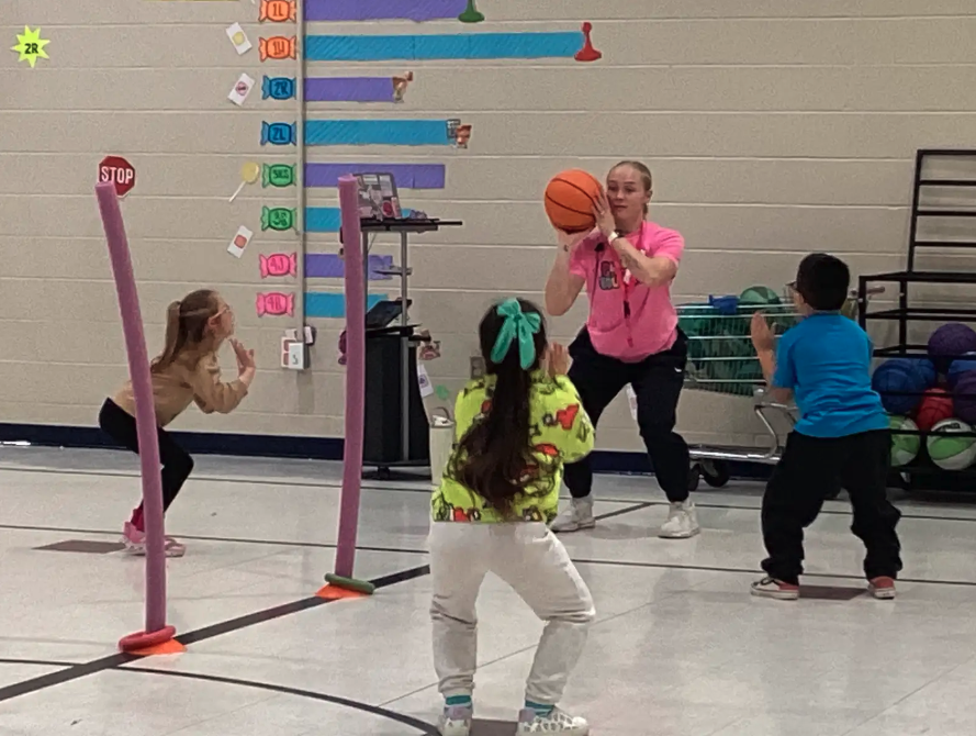 Coach Harrison teaching first grade students how to "load and explode" when shooting hoops