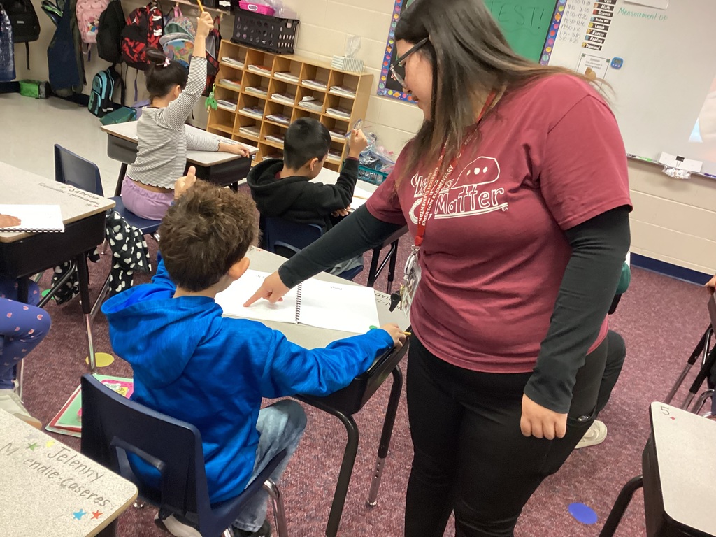 Ms. Torres helping a student during an art lesson
