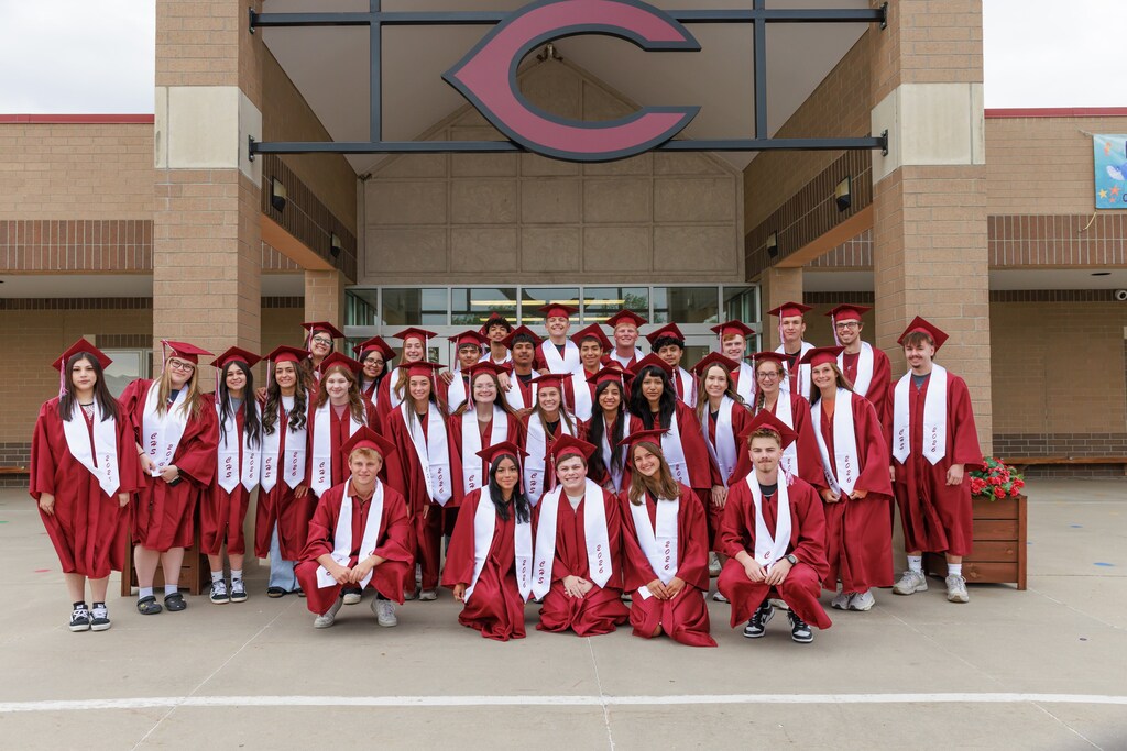 32 male and female graduating seniors from columbus high school posed in front of Centennial Elementary in their caps and gowns after their graduation walk through the halls.