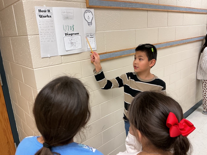 Student exStudent explaining his invention to peers.plaining his invention to peers.