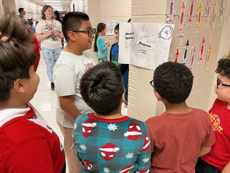 Student explaining his invention to peers.