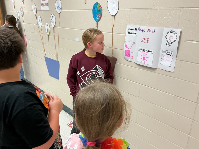 Student explaining their invention to peers.