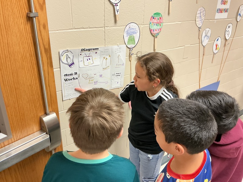 Student explaining their invention to peers.