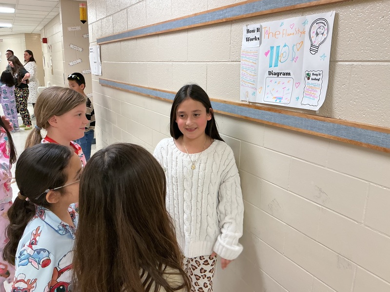 Student explaining their invention to peers.