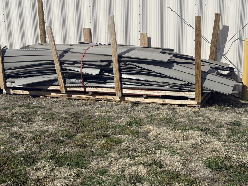 picture of leftover siding from the Cassette House possibly brown in color it is flipped over to protect it from the elements