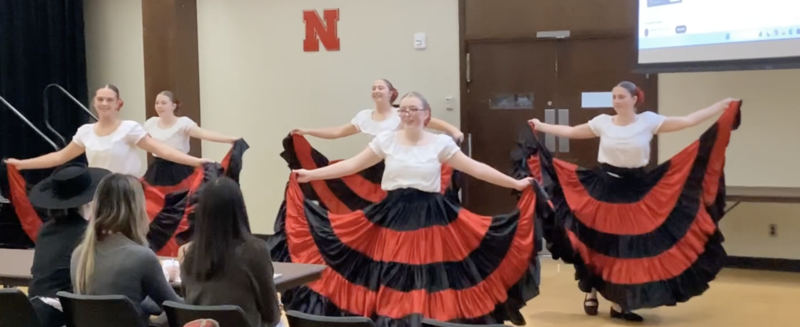 5 girls performing a folk dance dressed in culturally appropriate spanish skirts that are red and black with white tops