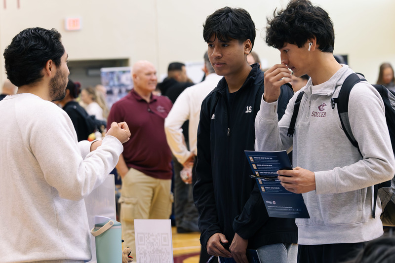Two CHS students talk with a college representative during a college/career fair.