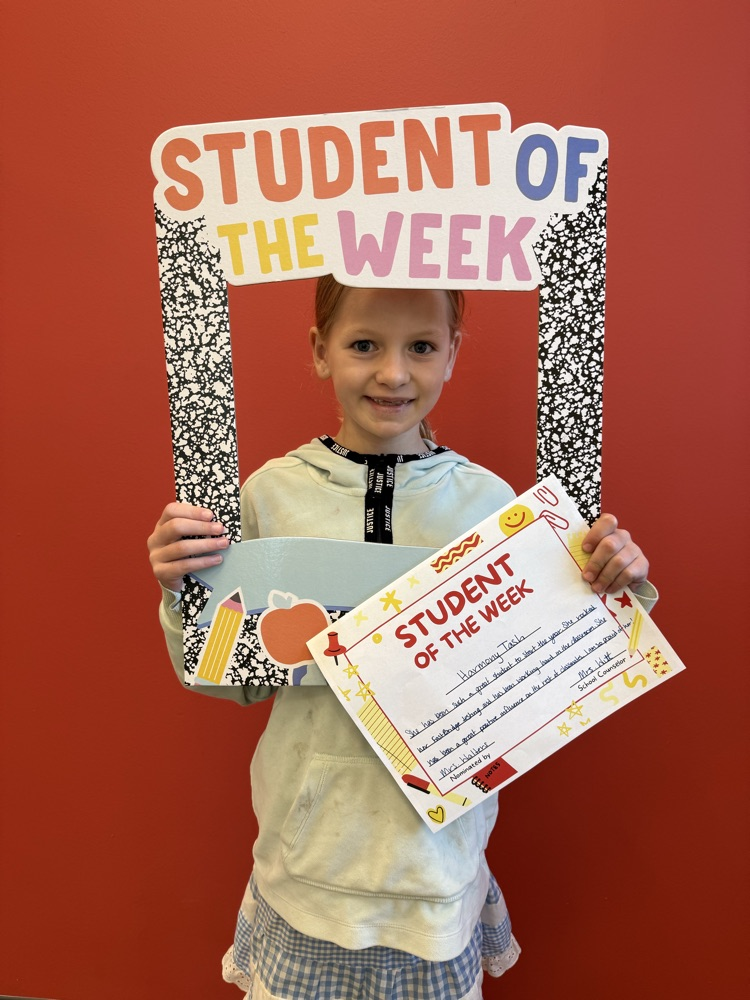 student holding up student of the week sign and smiling