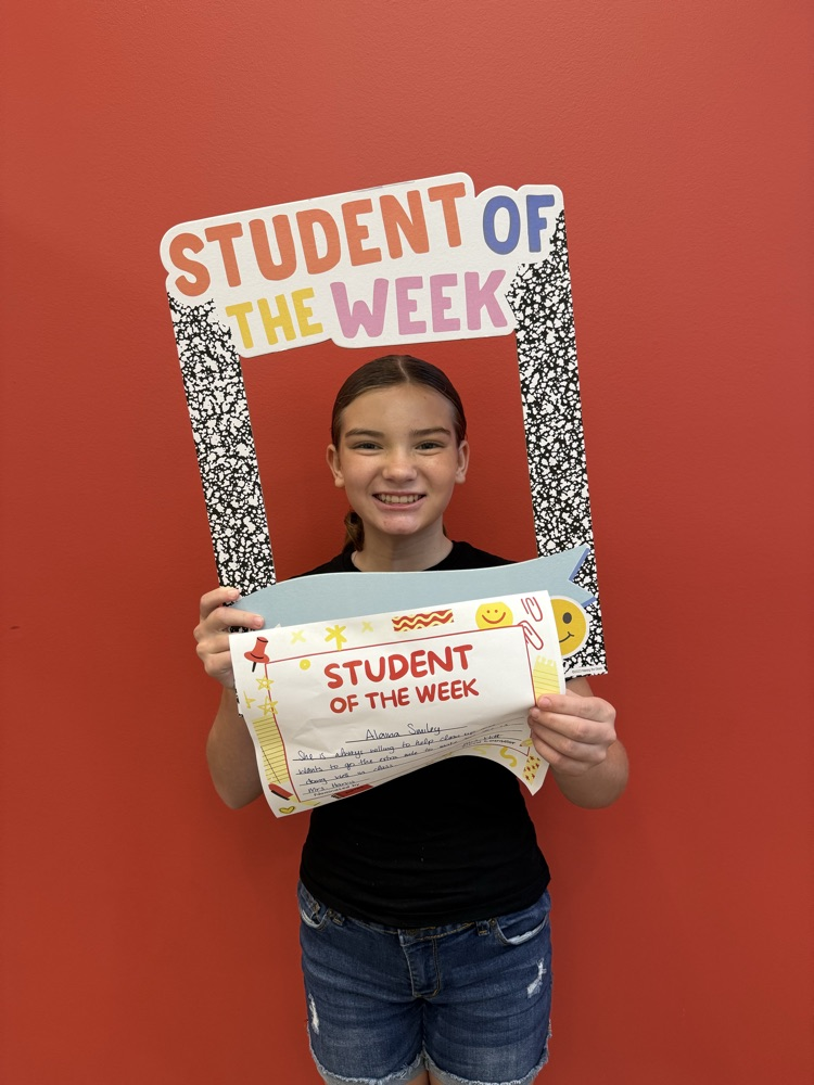 student of the week holding up a sign and smiling