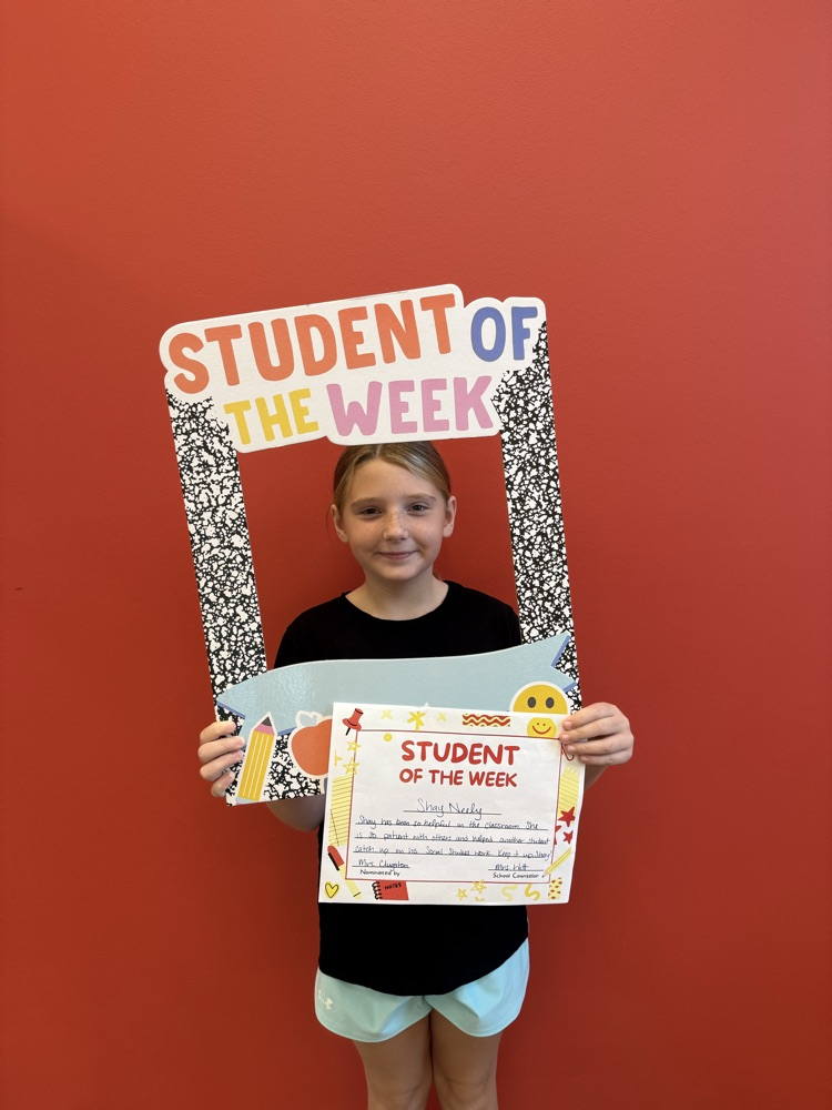 student of the week smiles and holds up a sign