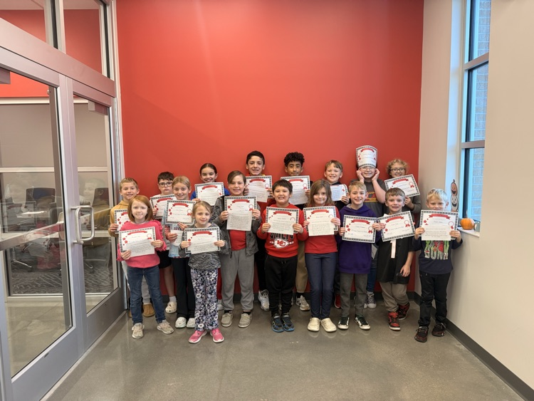 students stand holding their certificates and smiling 