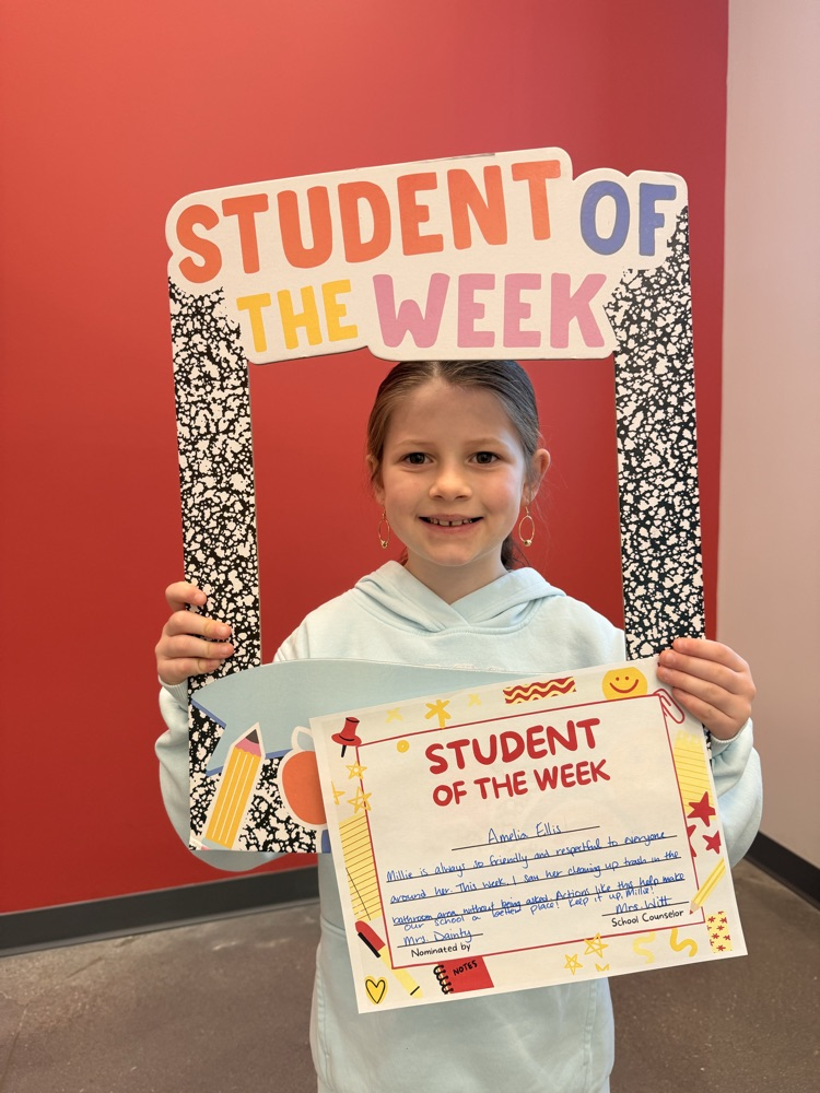 Millie holding student of the week sign and smiling