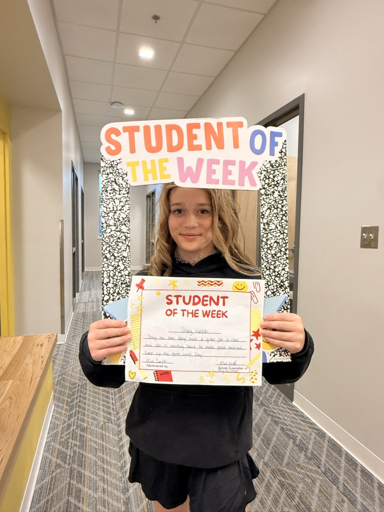 student holding sign and smiling