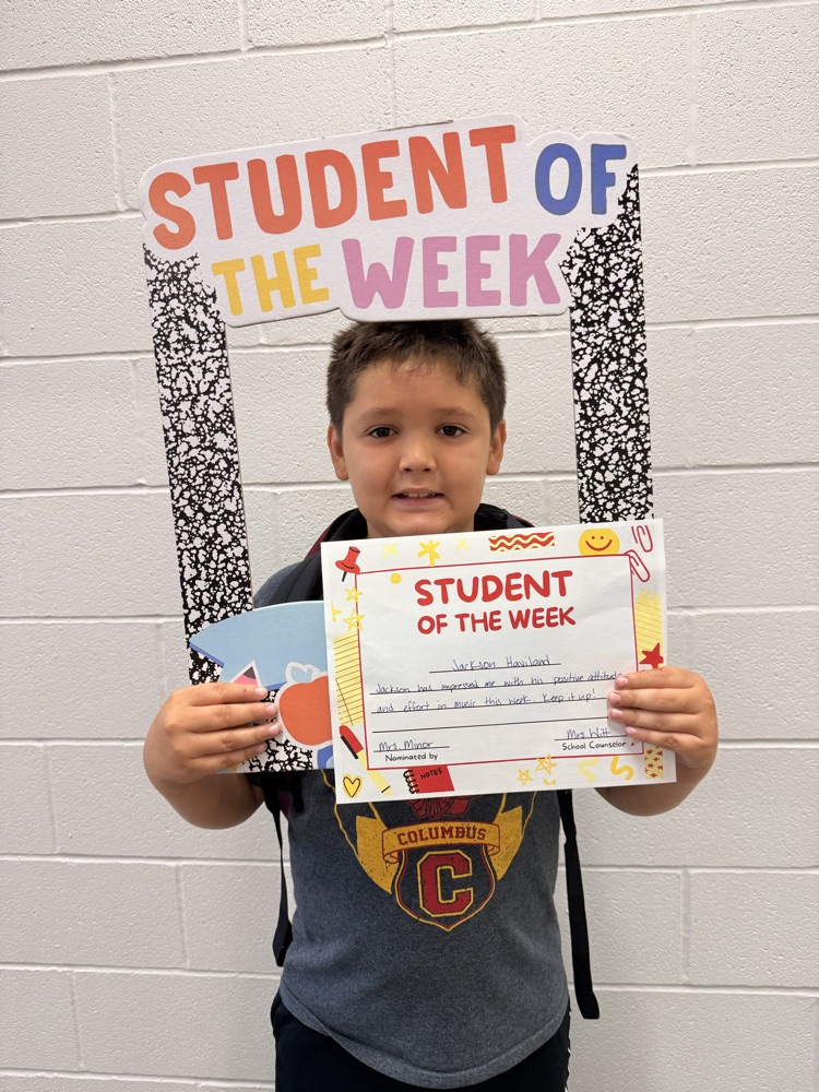 student smiles holding student of the week sign