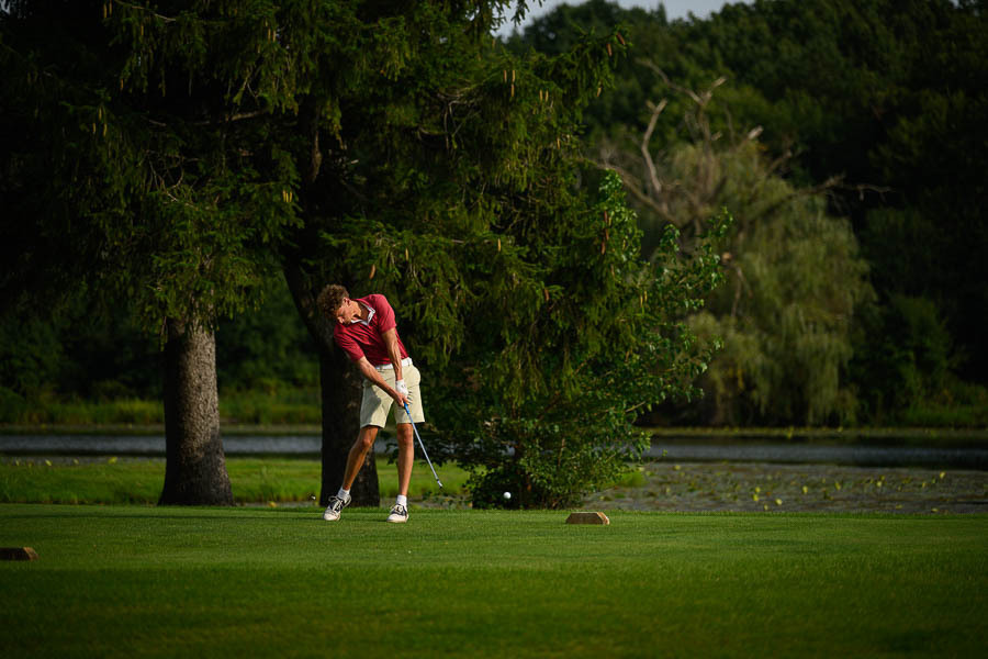 Boy hits a golf ball near a pond