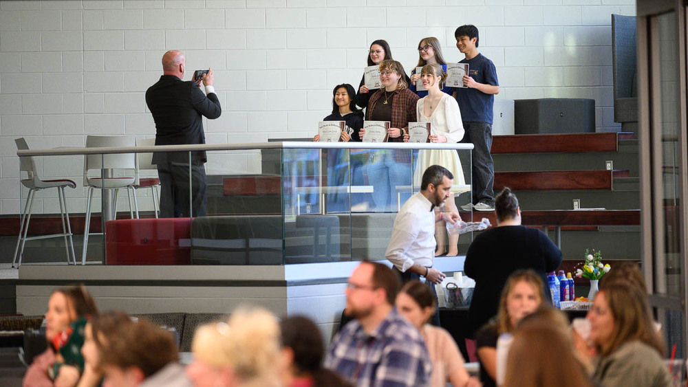 Dr. Berrie photographs a group of award recipients in the cafeteria.