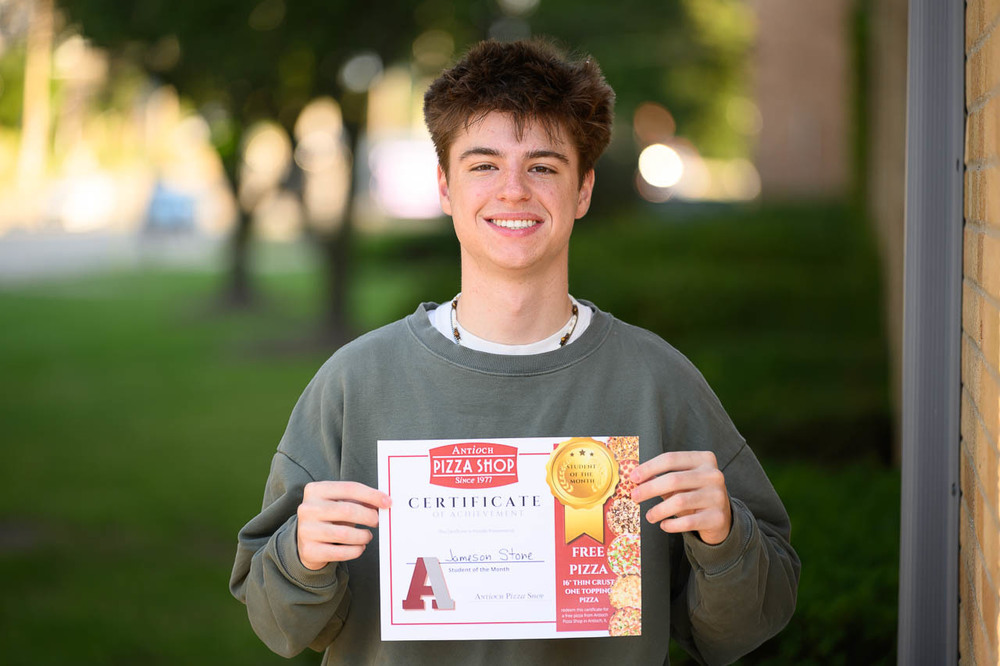 Student of the month, Jameson Stone outside ACHS with Antioch Pizza Gift Certificate.