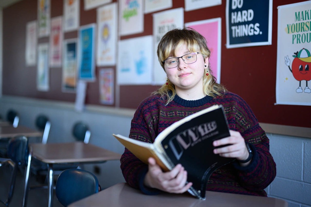 Portrait of Simona Valiokas in a classroom, holding a notebook.