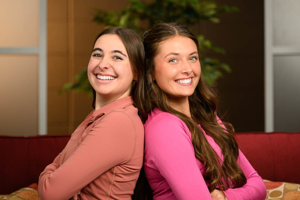 Two girls back to back. Head and shoulders.