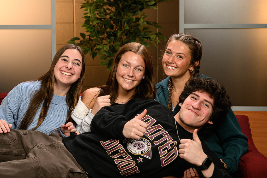 Four students smooshed onto a couch in the yearbook studio