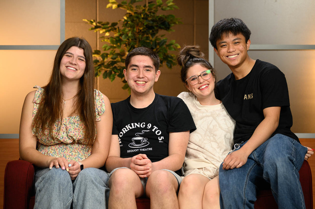 Four students sit on a couch, smiling.