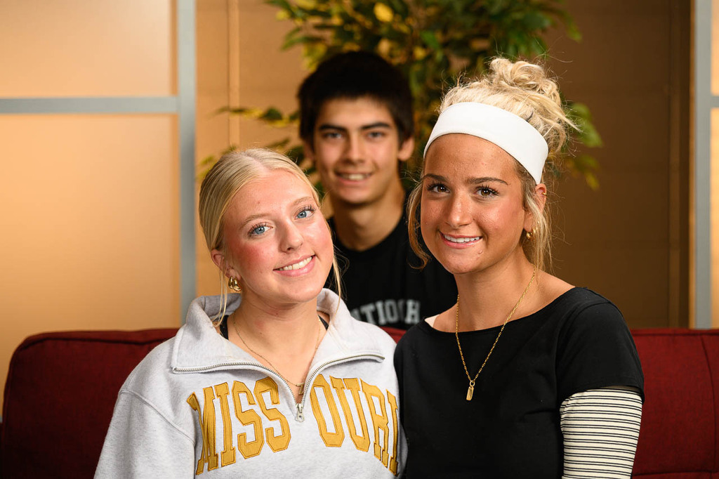 two girls and one boy on morning show set. Smiling. 