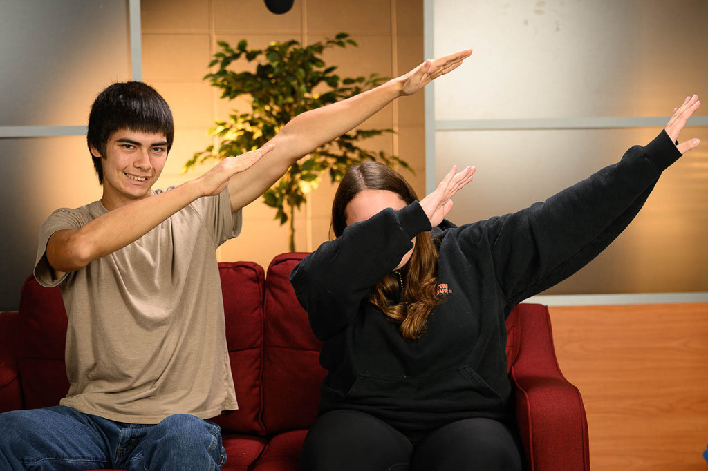 Two students dab on a couch.