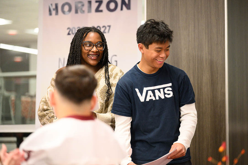 A student wearing a black Vans shirt and a woman smiling together on stage during an award presentation.
