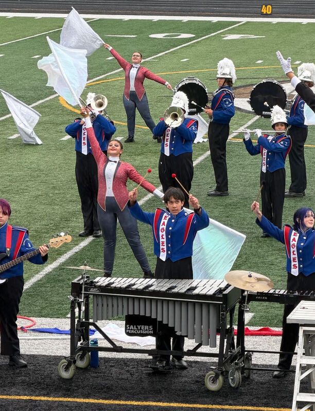 Student Martching Band Performing with instruments and flags