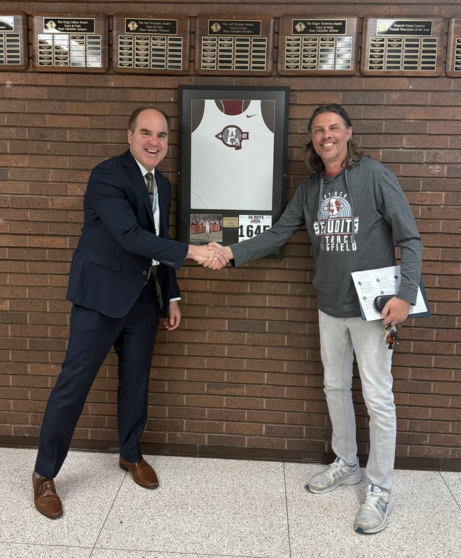 Two men shaking hands under a frames jersey