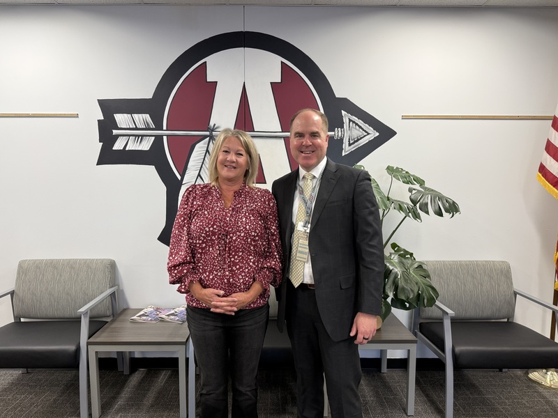 Woman in red shirt standing next to a man in a dark colored suit