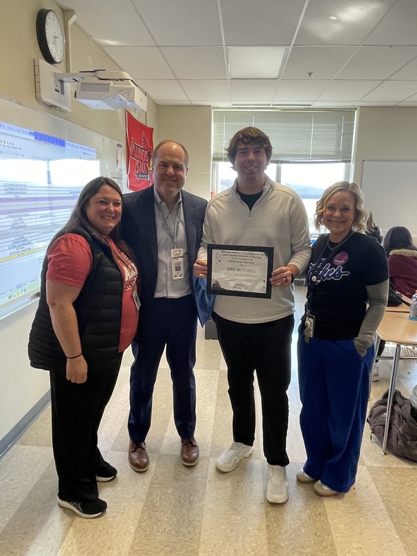 Four people awarding a man in white shirt with certificate