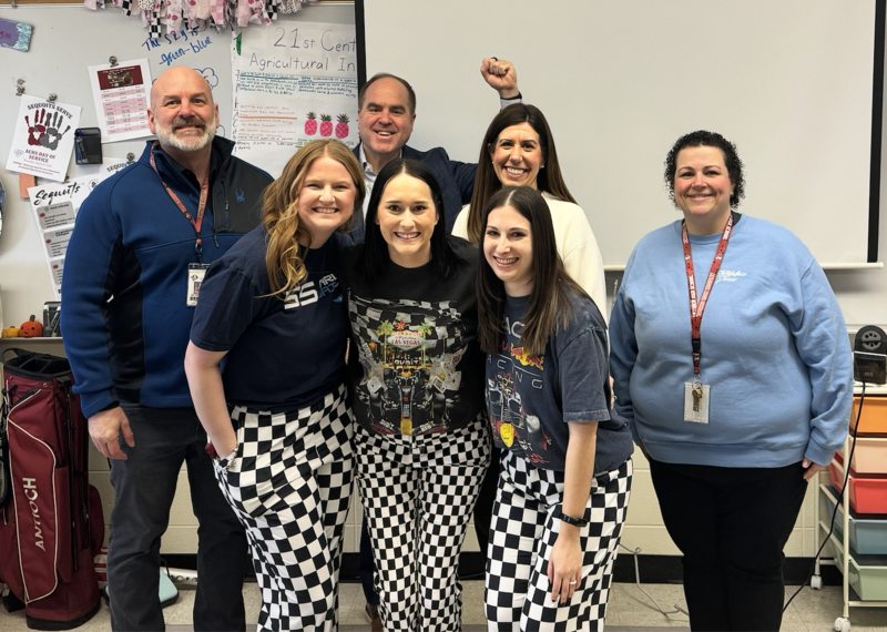 Group of 4 people standing behind 3 ladies in checkered pants 