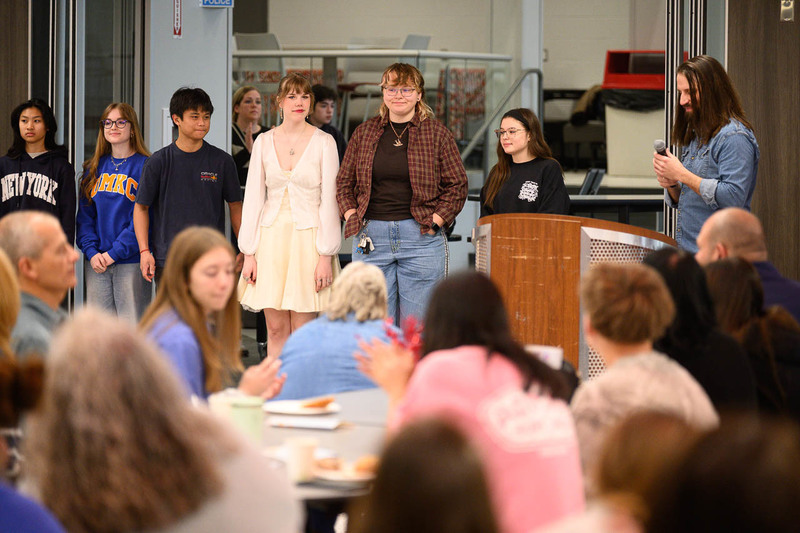 group of students stands at podium in crowded cafeteria