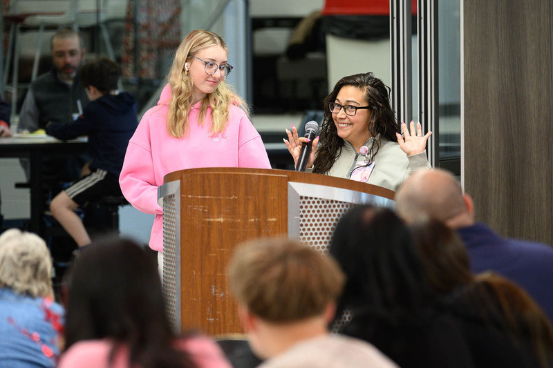 staff and student stand at podium
