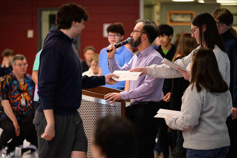 students hand out awards while teacher speaks