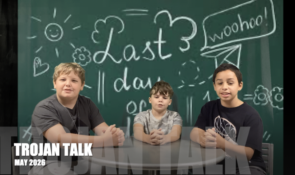 3 fifth graders sit at a table hosting the Trojan Talk 