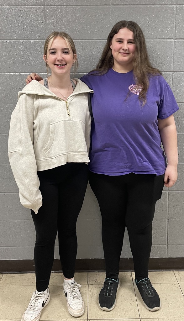 Hailey Schmidt and Kayleigh Rosol, who performed vocal solos at the District Music Contest in Mexico on March 14, stand smiling in front of a gray wall.