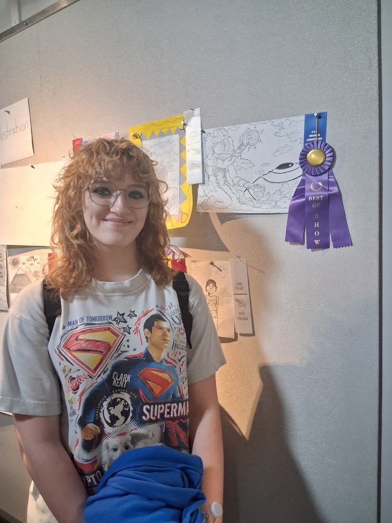 Student stands in front of their artwork.