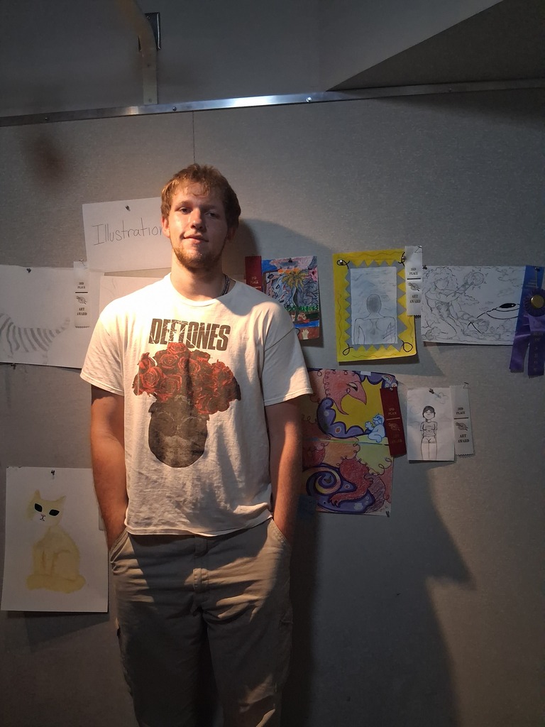 Student stands in front of their artwork.