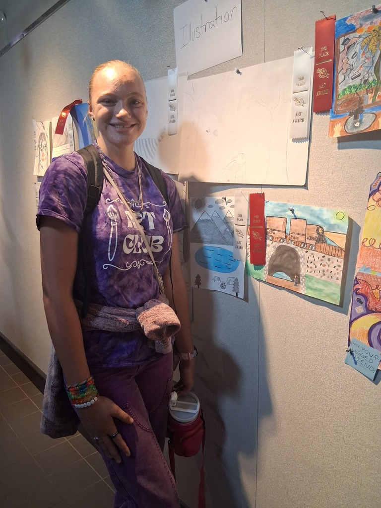 Student stands in front of their artwork.
